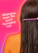Person with long hair using a pink comb against a pink background with text "detangles even the most damaged hair".